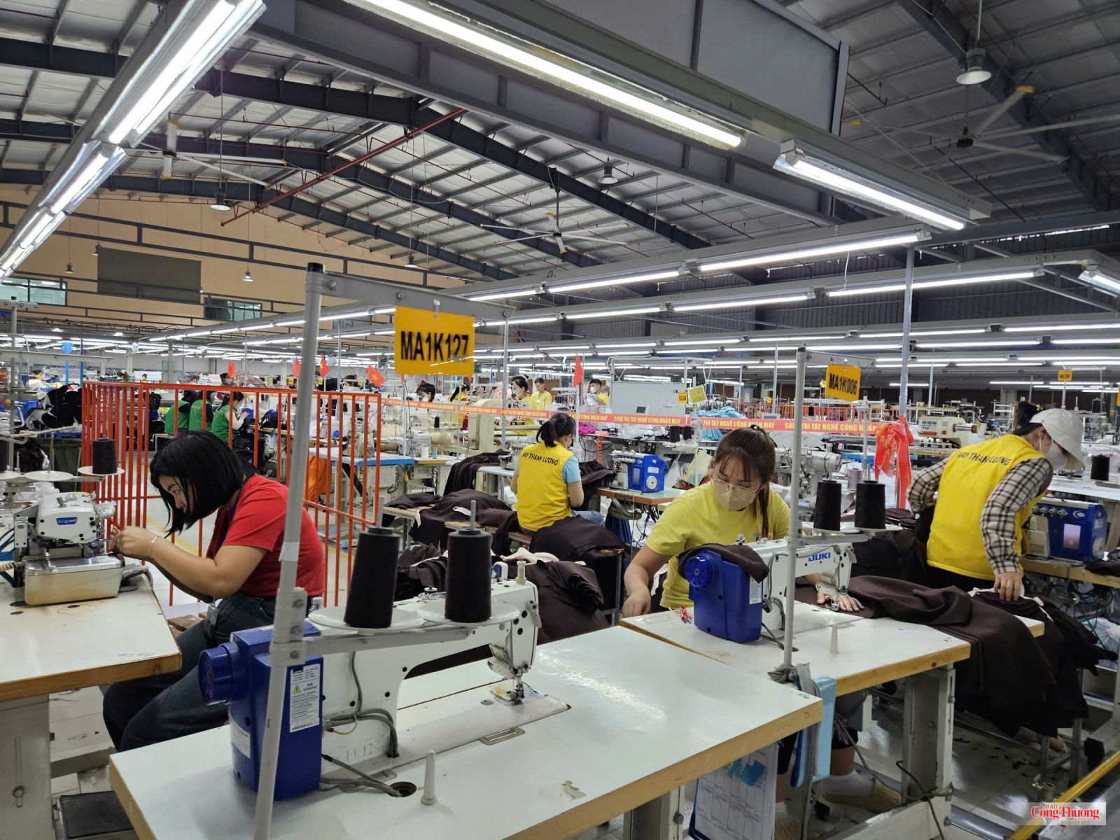 Công nhân vận hành máy may trên dây chuyền sản xuất hàng may mặc.